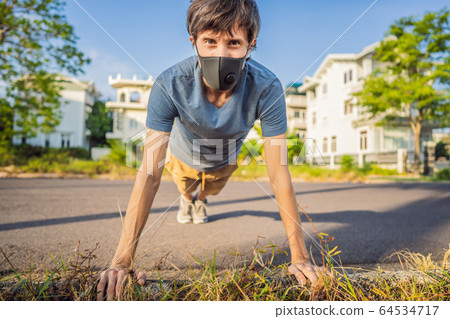 Young man in medical mask performing some workouts in the park during coronavirus quarantine 64534717