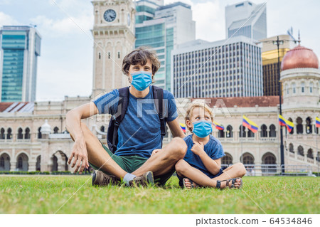 Dad and son in medical mask on background of Merdeka square and Sultan Abdul Samad Building Dad and son in medical mask on background of Merdeka square and Sultan Abdul Samad Building 64534846