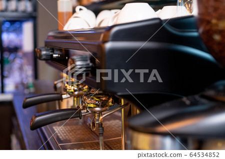 Modern coffee machine with two black plastic handles and pile of porcelain cups Modern coffee machine with two black plastic handles and pile of porcelain cups 64534852