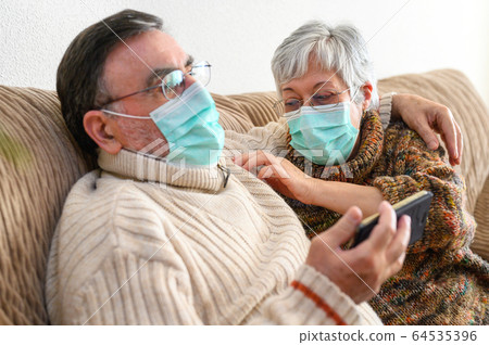 Coronavirus. Stay at home, lifestyle. Cheerful Elderly couple sitting on a sofa on a quarantine at Coronavirus. Stay at home, lifestyle. Cheerful Elderly couple sitting on a sofa on a quarantine at 64535396