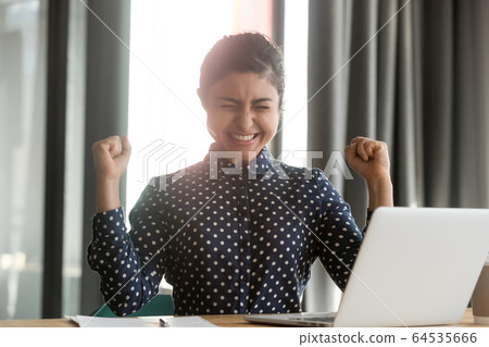 Happy overjoyed indian business woman winner celebrate computer win Happy overjoyed indian business woman winner celebrate computer win 64535666