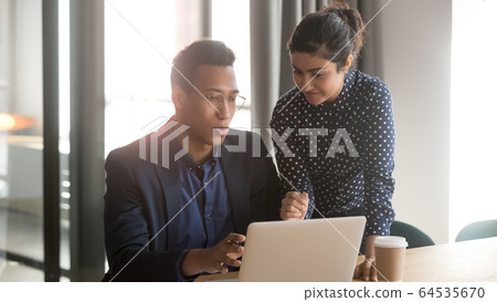 Indian mentor coworker talk help black intern explain computer work Indian mentor coworker talk help black intern explain computer work 64535670