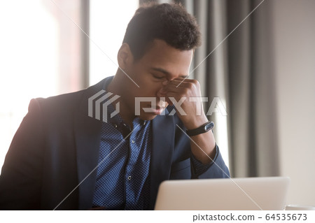 Frustrated stressed black businessman feel eye strain headache at work Frustrated stressed black businessman feel eye strain headache at work 64535673