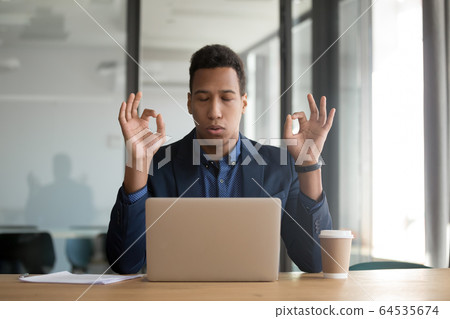 Calm mindful black businessman in suit meditate at work desk Calm mindful black businessman in suit meditate at work desk 64535674