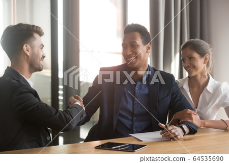 Satisfied mixed ethnicity young couple clients customers handshake advisor 64535690