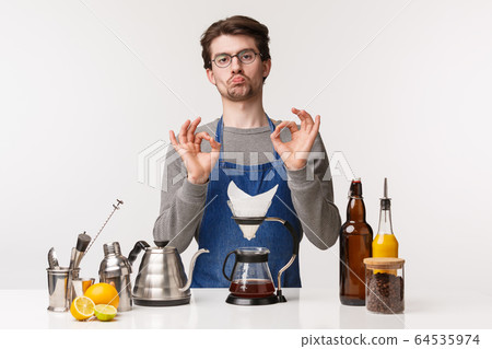 Barista, cafe worker and bartender concept. Portrait of impressed handsome young man show not bad, approval or like sign okay gesture, stand in apron near bar counter with filter coffee 64535974