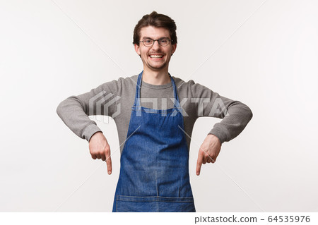 Portrait of enthusiastic friendly smiling male employee invite customers to visit their shop, enjoy delicious coffee and desserts, pointing fingers down grinning at camera, wear apron over shirt Portrait of enthusiastic friendly smiling male employee invite customers to visit their shop, enjoy delicious coffee and desserts, pointing fingers down grinning at camera, wear apron over shirt 64535976