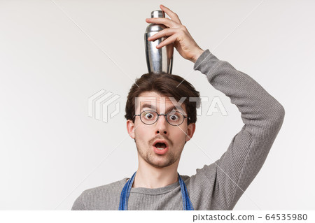 Close-up portrait of enthusiastic funny, handsome male employee, bartender or barista make shocked or surprised expression holding cocktail shaker on head balancing, white background Close-up portrait of enthusiastic funny, handsome male employee, bartender or barista make shocked or surprised expression holding cocktail shaker on head balancing, white background 64535980