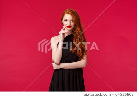 Elegance, fashion and woman concept. Portrait of seducative good-looking redhead woman in slim elegant black dress, red lipstick and evening makeup, look daring and sassy, red background Elegance, fashion and woman concept. Portrait of seducative good-looking redhead woman in slim elegant black dress, red lipstick and evening makeup, look daring and sassy, red background 64536602