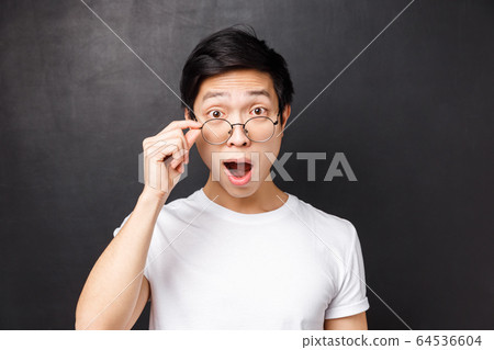 Close-up portrait of excited and wondered, intrigued asian man touch glasses, look excited and interested at camera, open mouth fascinated, listen to interesting suggestion, black background Close-up portrait of excited and wondered, intrigued asian man touch glasses, look excited and interested at camera, open mouth fascinated, listen to interesting suggestion, black background 64536604