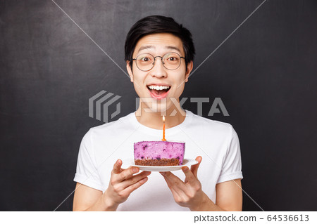 Celebration, holiday and birthday concept. Close-up portrait of amazed and happy young asian man holding b-day cake and smiling amused, throw party, blow out candle for making wish Celebration, holiday and birthday concept. Close-up portrait of amazed and happy young asian man holding b-day cake and smiling amused, throw party, blow out candle for making wish 64536613