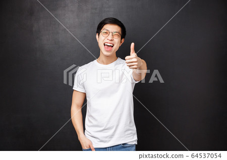 Lifestyle and people concept. Happy and satisfied young asian modern guy customer left impressed and pleased after attending awesome concert, show thumb-up in approval and wink joyfully 64537054