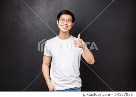 Lifestyle and people concept. Handsome young asian man in white t-shirt, sunglasses standing over black background show thumb-up and nod in agreement, smiling satisfied, leave positive feedback Lifestyle and people concept. Handsome young asian man in white t-shirt, sunglasses standing over black background show thumb-up and nod in agreement, smiling satisfied, leave positive feedback 64537056