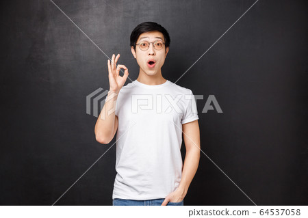 Amazed and enthusiastic young surprised asian guy left speechless and impressed after seeing premier of new movie, show okay sign look astounded standing black background Amazed and enthusiastic young surprised asian guy left speechless and impressed after seeing premier of new movie, show okay sign look astounded standing black background 64537058