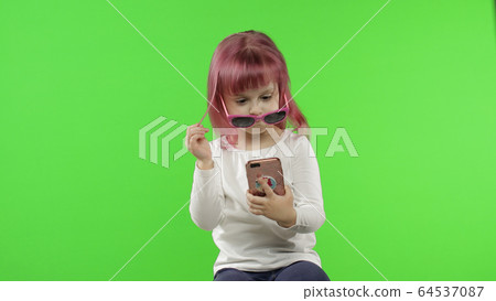 Girl using smartphone. Child emotionally talking on mobile phone, take selfie Girl using smartphone. Child emotionally talking on mobile phone, take selfie 64537087