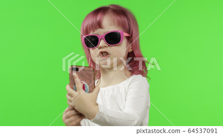 Girl using smartphone. Child emotionally talking on mobile phone, take selfie Girl using smartphone. Child emotionally talking on mobile phone, take selfie 64537091