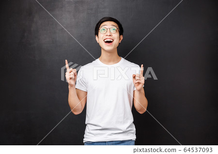 Excited guy admiring how something beautiful falling from sky, pointing looking up astonished and happy, cheering about cool thing, new product in stock, stand black background 64537093