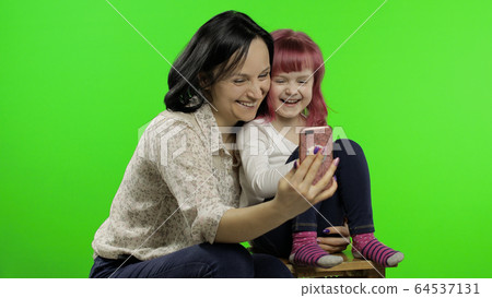 Mother, daughter holding, using smart phone talking on video call. Social media Mother, daughter holding, using smart phone talking on video call. Social media 64537131