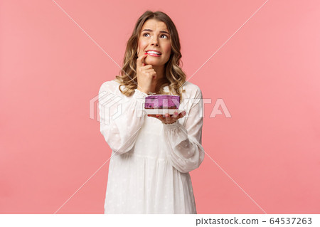 Holidays, spring and party concept. Portrait of hesitant and alarmed young blond girl thinking, hesitating over eating or not delicious dessert with calories, being on diet, resist temptation Holidays, spring and party concept. Portrait of hesitant and alarmed young blond girl thinking, hesitating over eating or not delicious dessert with calories, being on diet, resist temptation 64537263