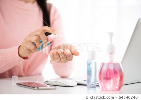 Closeup woman hands using alcohol spray to her 64540240