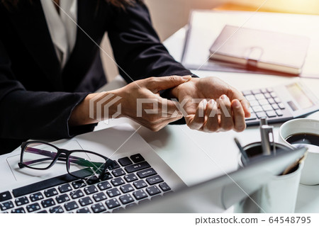 Stressed business woman suffering from wrist pain Stressed business woman suffering from wrist pain 64548795