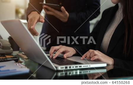 Business documents on office table with smart phone, tablet and laptop computer and graph with social network diagram and two colleagues discussing data in office. 64550268