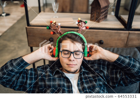 Happy man in headphones relaxing on the sofa at home Happy man in headphones relaxing on the sofa at home 64553331