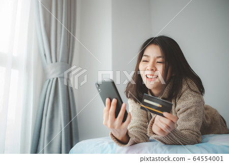 women lying on the bed and using smartphone for 64554001