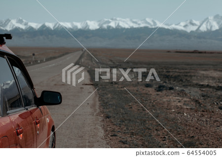 Open road to mountain with car in the left of the frame 64554005
