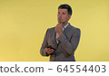 Tall man in suit holding one hand on chin, looking on smartphone and thinking about something. 64554403