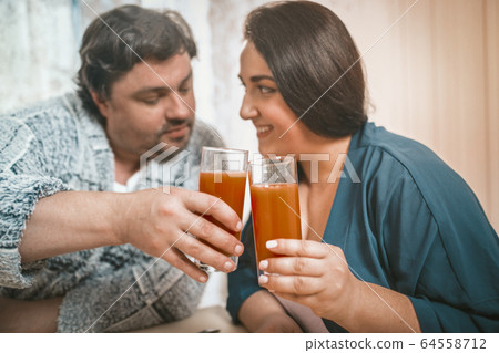 Couple Flirting And Clinking With Glasses Of Juice Couple Flirting And Clinking With Glasses Of Juice 64558712