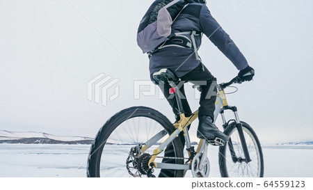 Man is riding bicycle on the ice. Ice of frozen Lake Baikal. Tee 64559123