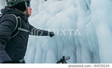 Man is riding bicycle near ice grotto. Rock with ice caves icicl 64559134