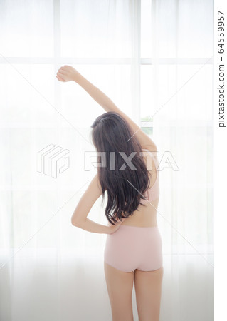 Beautiful young asian woman waking up in the morning stand stretching arms in the bedroom Beautiful young asian woman waking up in the morning stand stretching arms in the bedroom 64559957