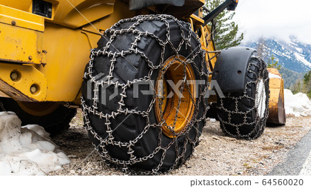 Front loader for snow removal with metal snow chains on wheels. Snow removal in the mountains. 64560020