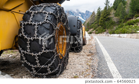 Front loader for snow removal with metal snow chains on wheels. Snow removal in the mountains. 64560025