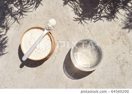Closeup collagen with a spoon and glass of water on concrete background.  64560200