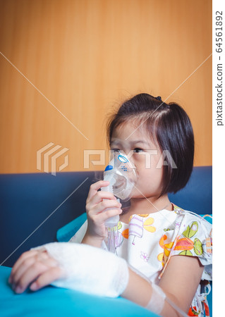 Sad asian child holds a mask vapor inhaler for treatment of asthma. Sad asian child holds a mask vapor inhaler for treatment of asthma. 64561892
