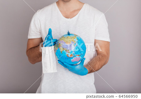 Man is wearing mask holding globe. Covid concept. Isolated white background Man is wearing mask holding globe. Covid concept. Isolated white background 64566950
