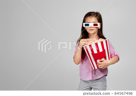 child girl wearing red-blue 3d glasses and eating popcorn child girl wearing red-blue 3d glasses and eating popcorn 64567496