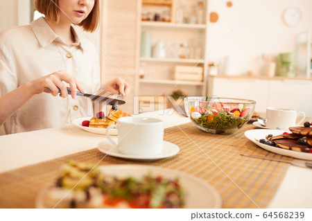 Woman Enjoying Delicious Desserts in Cozy Kitchen 64568239