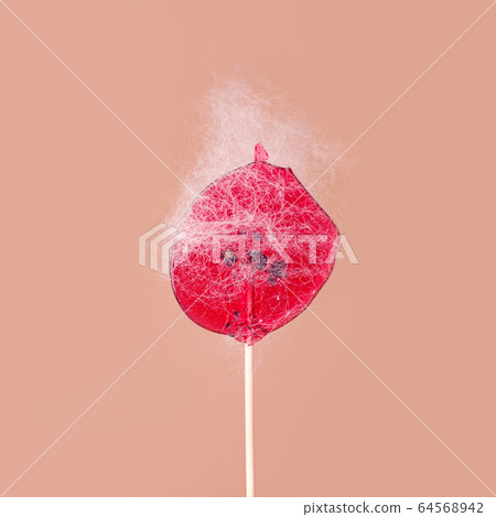 Pink lollipop with sticky hair on beige 64568942