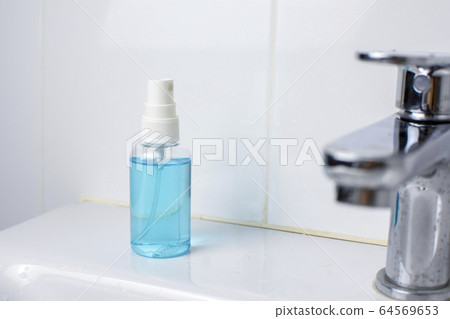 Alcohol sanitizer spray bottle on wash basin in toilet. Alcohol sanitizer spray bottle on wash basin in toilet. 64569653