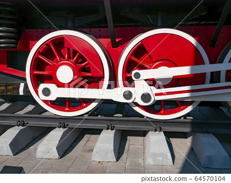 Red wheels of an old railway locomotive. 64570104