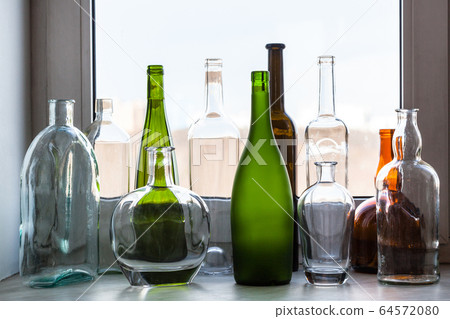 various empty bottles on sill of home window 64572080