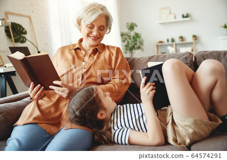 Cheerful grandmother and granddaughter reading 64574291