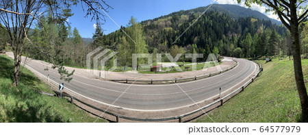 Italy, twisted road of the Alps mountains, without cars, a picturesque view of mountains, sunny weather, Zone for picnic, benches for rest Italy, twisted road of the Alps mountains, without cars, a picturesque view of mountains, sunny weather, Zone for picnic, benches for rest 64577979