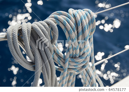 Close-up view of sailboat ropes at sunny weather, pulleys and ropes on the mast, Yachting sport, ship equipment, sea is on background 64578177