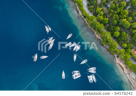 Aerial view of a much chaotically standing boats in a bay at sunset, Croatia, coastline with azure water and green trees, Transparent water, reef under water 64578242