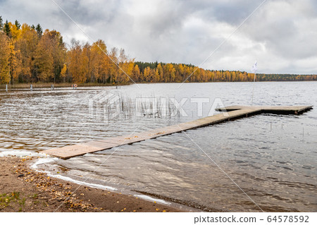 The Long pier on the lake, Terrace at the lake, the Autumn at the lake Boroye, Boats at a pier, Valday national park, Russia, panoramic image, golden trees, Wooden lodges, cloudy weather The Long pier on the lake, Terrace at the lake, the Autumn at the lake Boroye, Boats at a pier, Valday national park, Russia, panoramic image, golden trees, Wooden lodges, cloudy weather 64578592